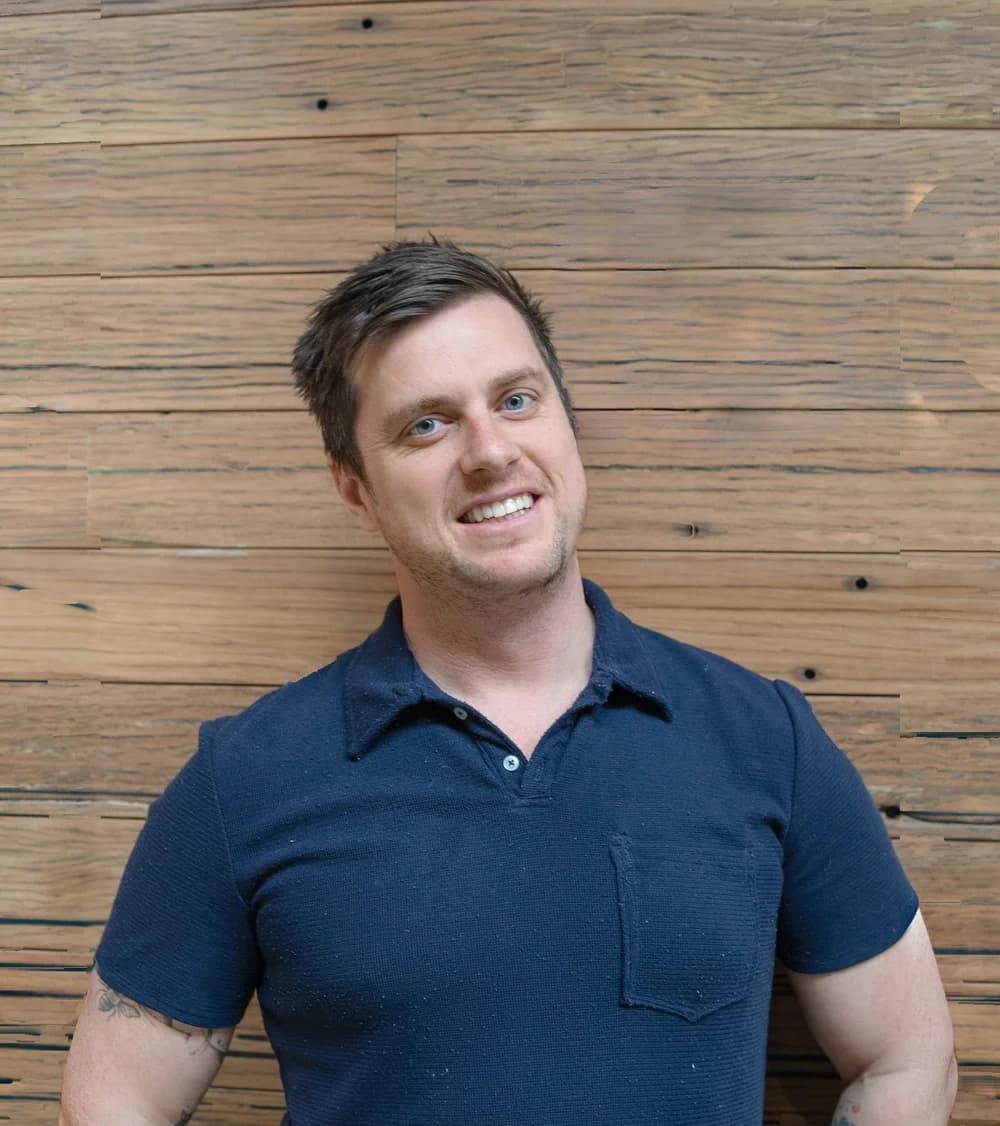 Brendan Smith, finance broker at Tenon Finance, in a navy polo shirt, smiling, in front of a recycled timber wall