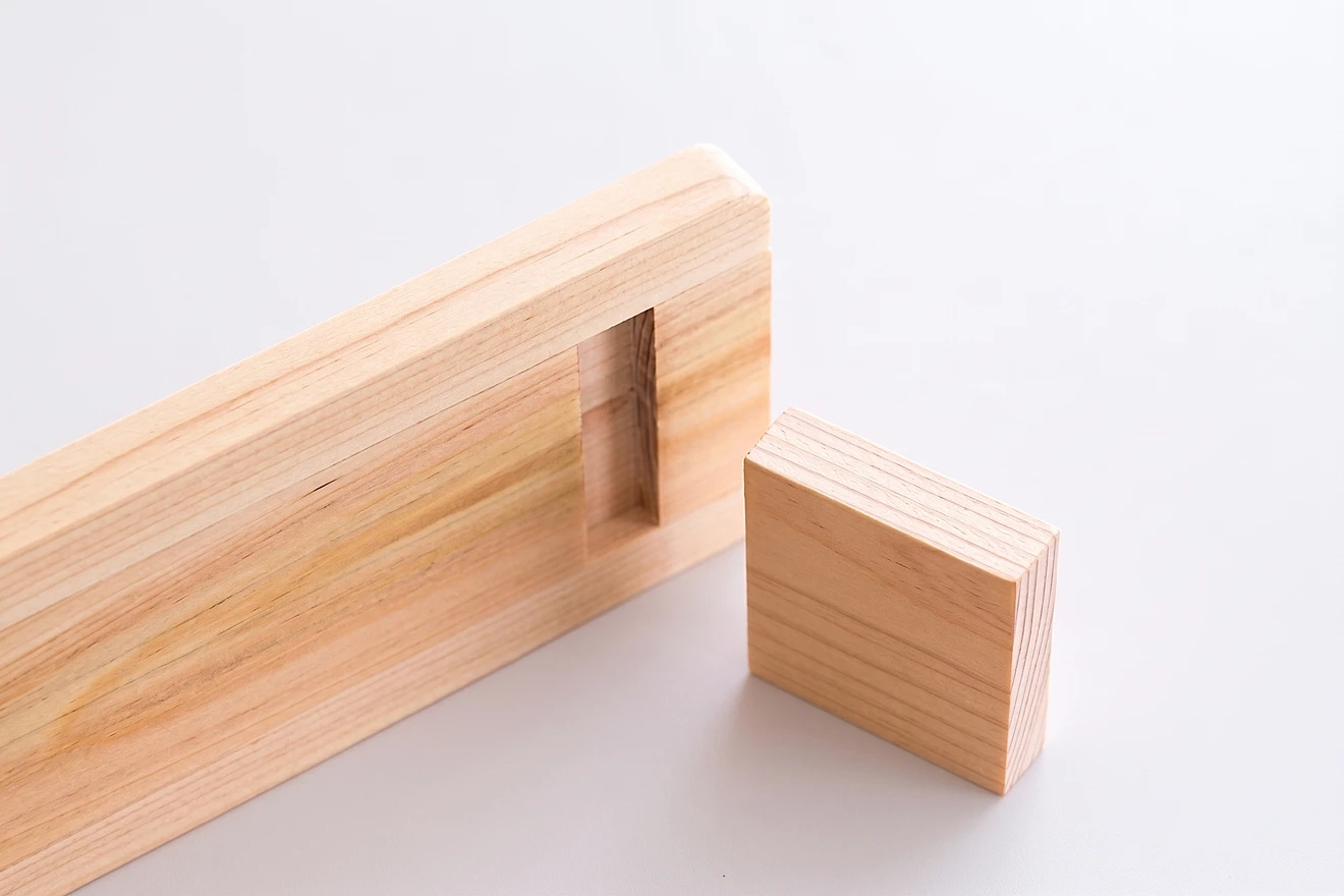 A mortise and tenon joint in pale timber before assembly: the tenon standing beside the board with the mortise cut into it