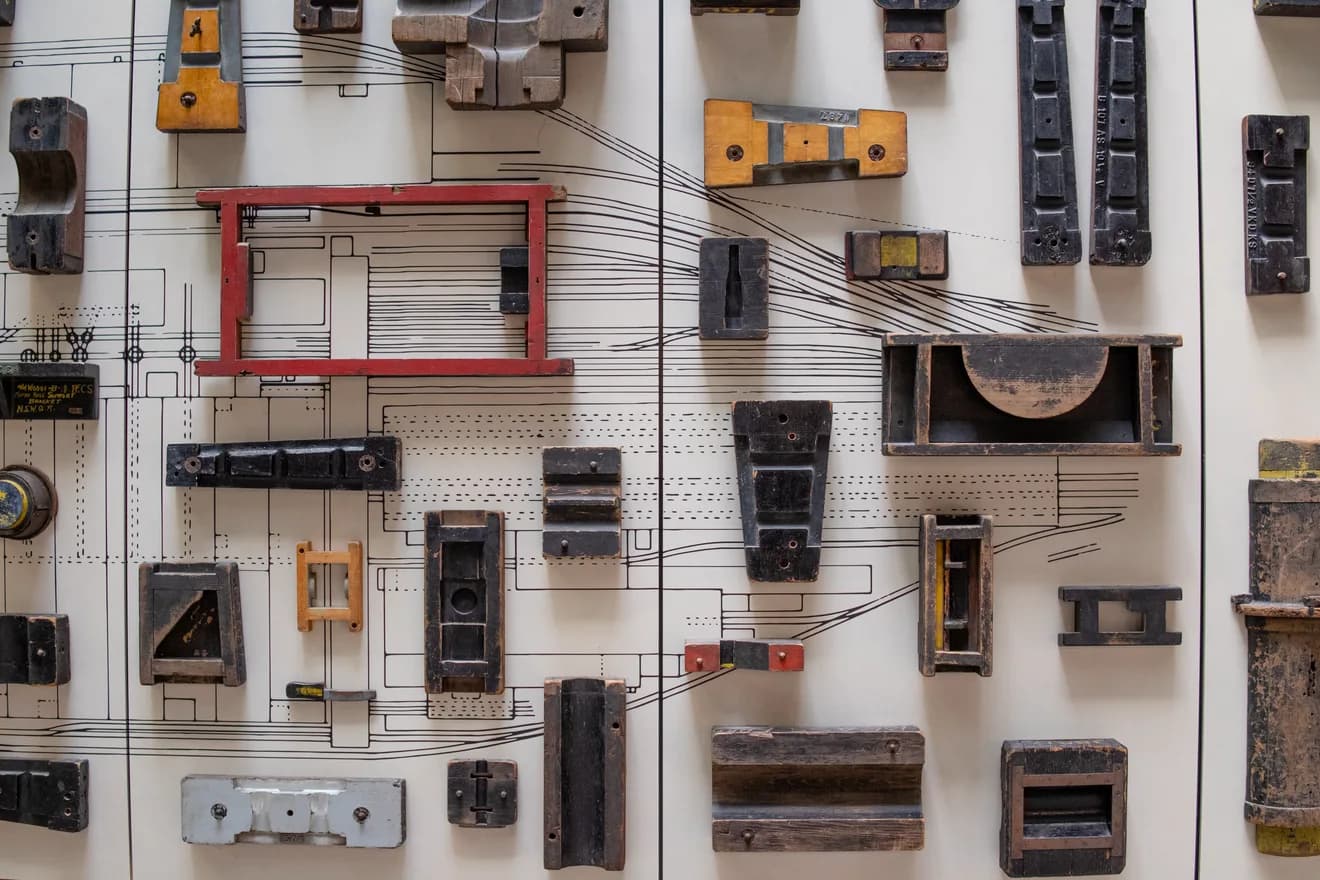 Wooden foundry patterns of many shapes pinned over a technical drawing